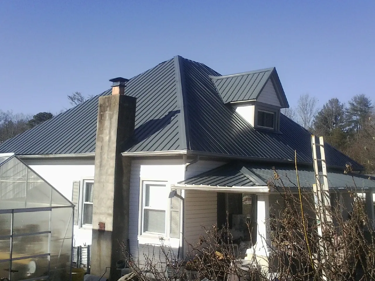 Dark blue standing seam metal roof on a white farmhouse with dormer — Slate & Tile Roof Repair by Roofing Brothers in Allyn