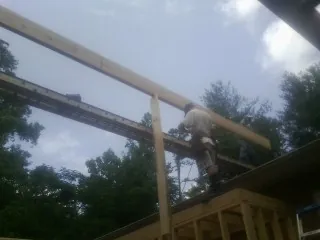 Carpenter setting a ridge beam over a new addition frame — Ice Dam Removal by Roofing Brothers in Allyn