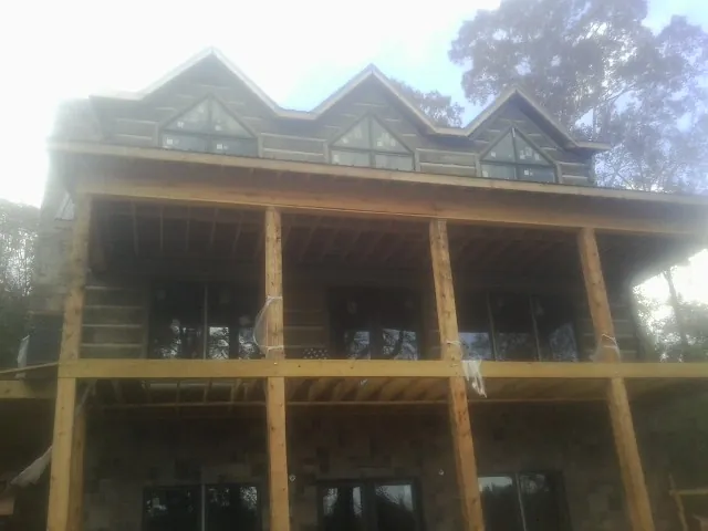 Dormers and porch framing on a large log home under construction — Roof Coating work by our crew in Allyn